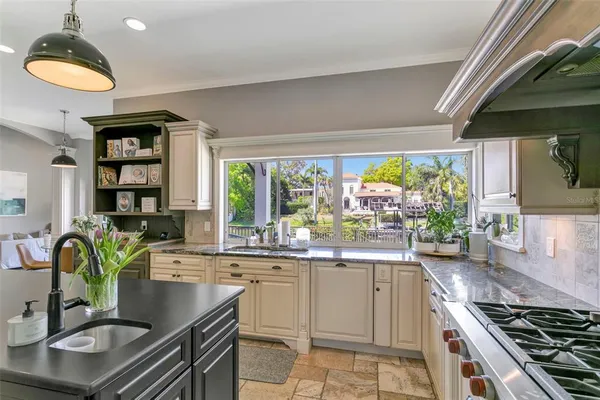a kitchen with stainless steel appliances granite countertop a sink a stove and a wooden cabinets