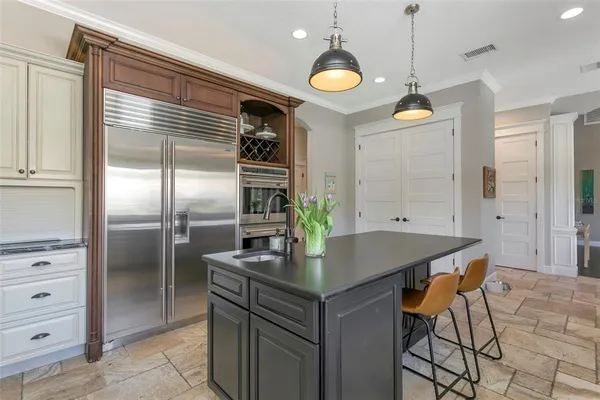 a kitchen with stainless steel appliances kitchen island granite countertop a table chairs and refrigerator