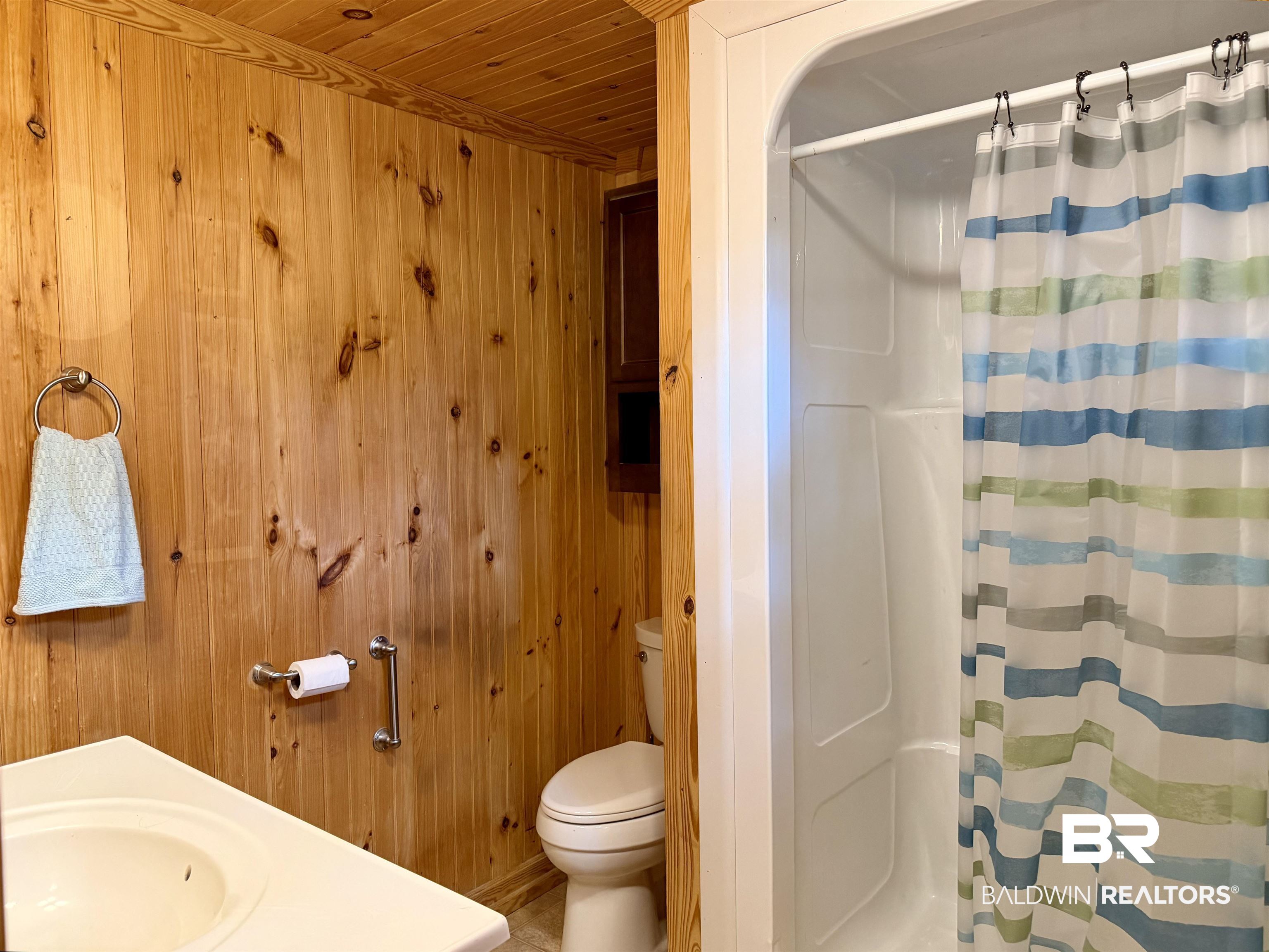 762 Buddy Lake Road Brewton, AL 36426 - Photo 12 of 20 Bathroom featuring natural wood plank walls, a white vanity with integrated sink, and a shower stall with a white surround