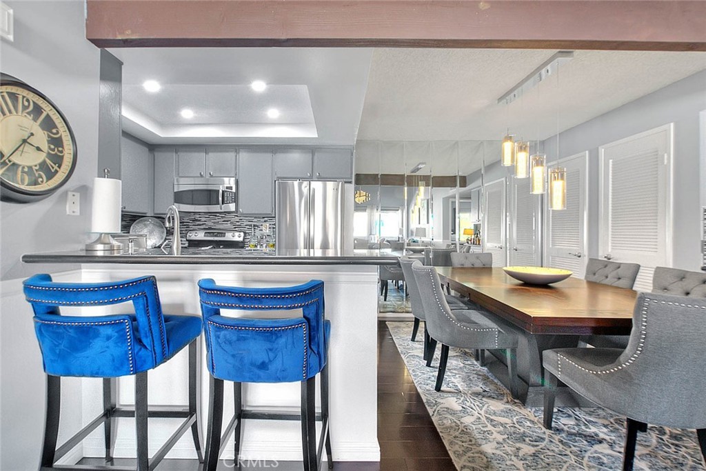 44 Carriage Way, Unit 108 Pomona, CA 91766 - Photo 15 of 44 a kitchen with stainless steel appliances kitchen island granite countertop a table chairs sink and cabinets