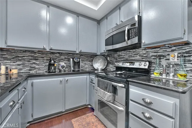 a kitchen with stainless steel appliances granite countertop a sink a stove and a microwave