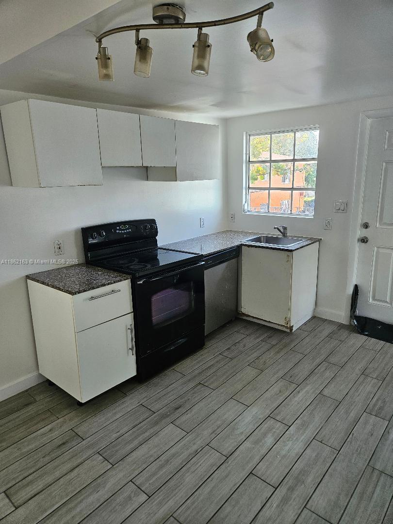 1035 Northwest 5th Street, Unit 3 Miami, FL 33128 - Photo 4 of 5 a kitchen with granite countertop a stove a sink and white cabinets with wooden floor