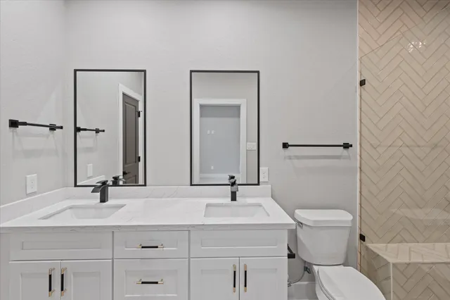 a bathroom with a granite countertop toilet sink and mirror