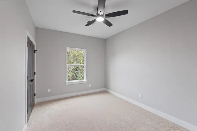 an empty room with windows and fan