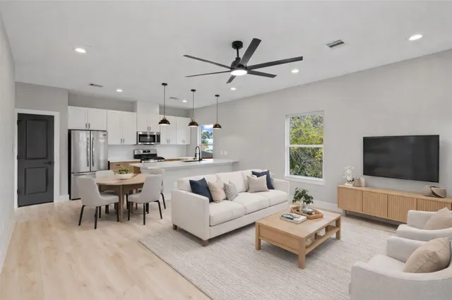 a living room with furniture and a flat screen tv with kitchen view