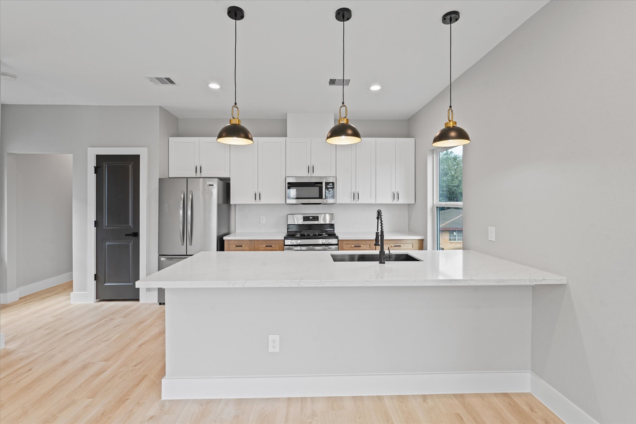 7349 Sandle Street, Unit B Houston, TX 77088 - Photo 7 of 19 a view of a kitchen with kitchen island stainless steel appliances a sink a refrigerator a stove a center island and wooden floor