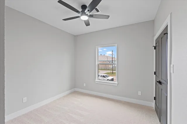 an empty room with windows and fan