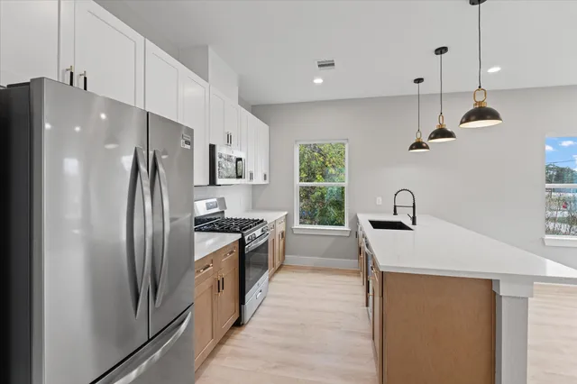 a kitchen with stainless steel appliances granite countertop a refrigerator a sink a stove and a sink with wooden floor