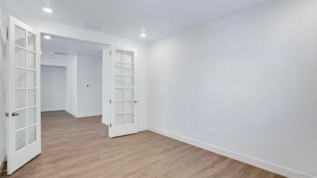 a view of an empty room with wooden floor and closet