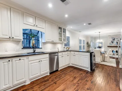 a kitchen with granite countertop white cabinets and white appliances with wooden floor