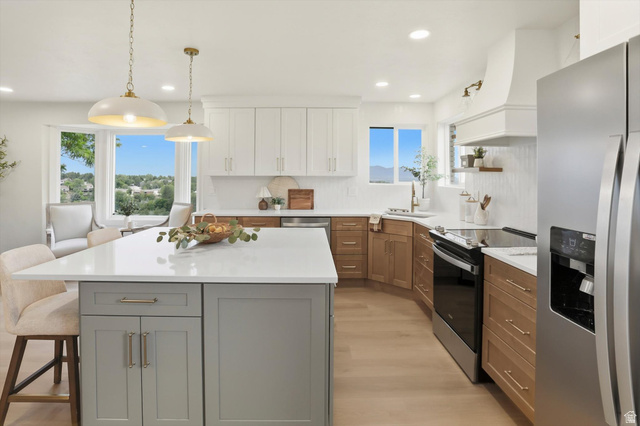 8760 Rustler Road Cottonwood Heights, UT 84093 - Photo 17 of 57 Spacious kitchen featuring a large central island with a light-colored countertop, recessed lighting, wood-finish flooring, two-tone cabinetry, and a stainless steel refrigerator