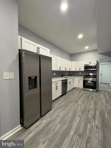 a large kitchen with stainless steel appliances a refrigerator and a stove top oven