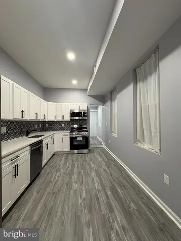 a large kitchen with kitchen island granite countertop a sink cabinets and stainless steel appliances