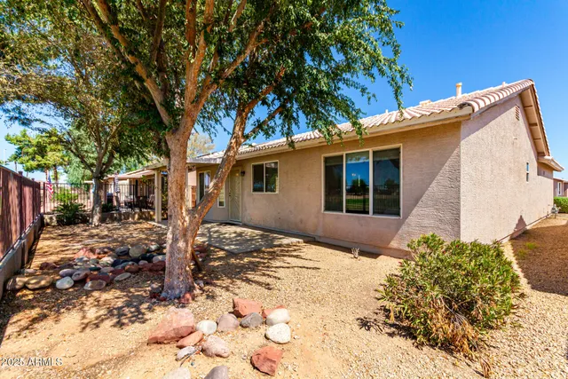 a backyard of a house with table and chairs under an umbrella