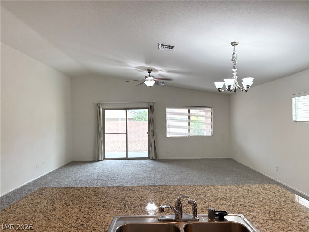 8231 Buffalo Ranch Avenue Las Vegas, NV 89147 - Photo 7 of 22 Granite counters overlook a spacious living area with vaulted ceilings and outdoor access.