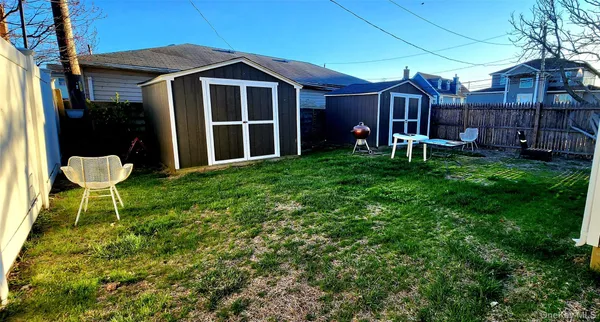 a view of a chair and table in backyard of the house