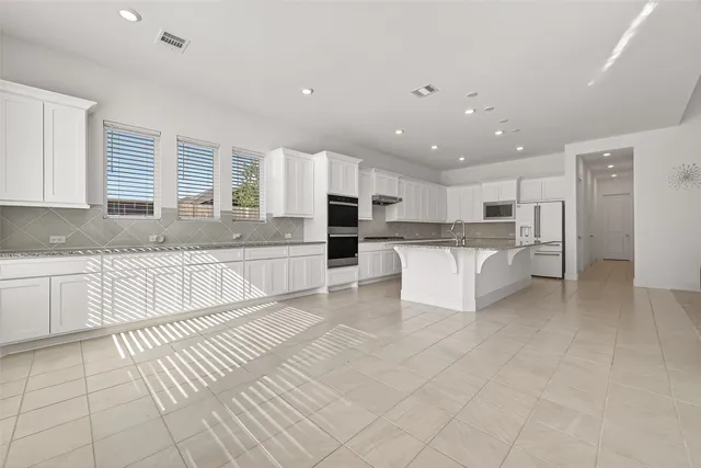 a large white kitchen with kitchen island a sink a counter and a large window
