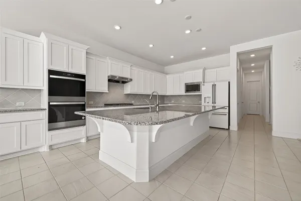 a large kitchen with stainless steel appliances granite countertop a stove a sink and a refrigerator
