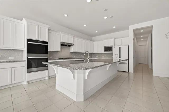 a large kitchen with stainless steel appliances granite countertop a stove a sink and a refrigerator