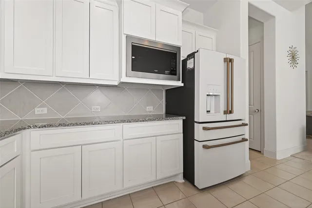 a kitchen with granite countertop white cabinets and stainless steel appliances