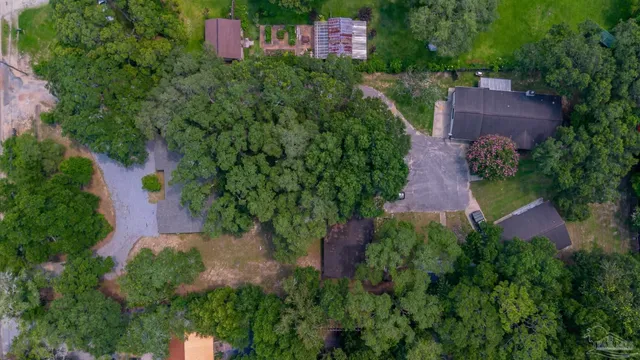 an aerial view of a house with a yard and trees all around