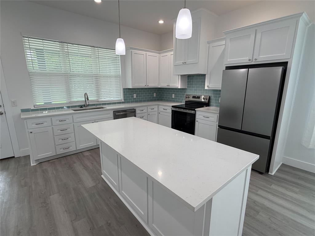 4200 Williams Road Bellmead, TX 76705 - Photo 6 of 22 a kitchen with a sink a kitchen island wooden cabinetry and stainless steel appliances
