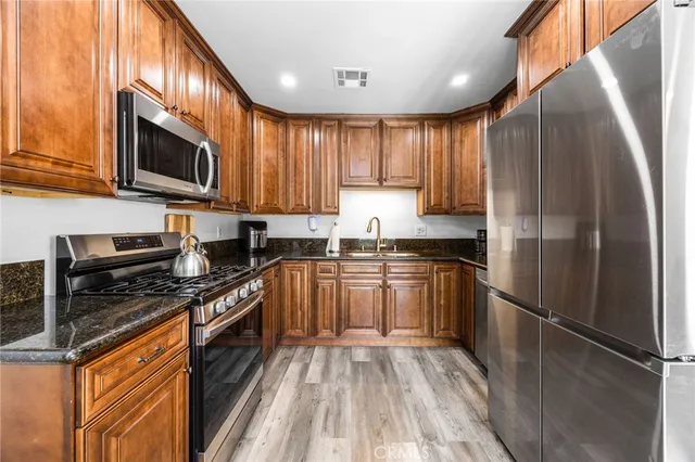 a kitchen with stainless steel appliances granite countertop a refrigerator a stove top oven a sink and dishwasher