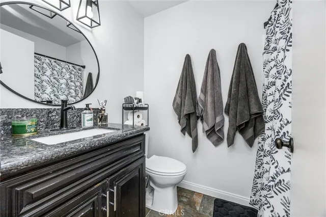 a bathroom with a granite countertop sink and a toilet