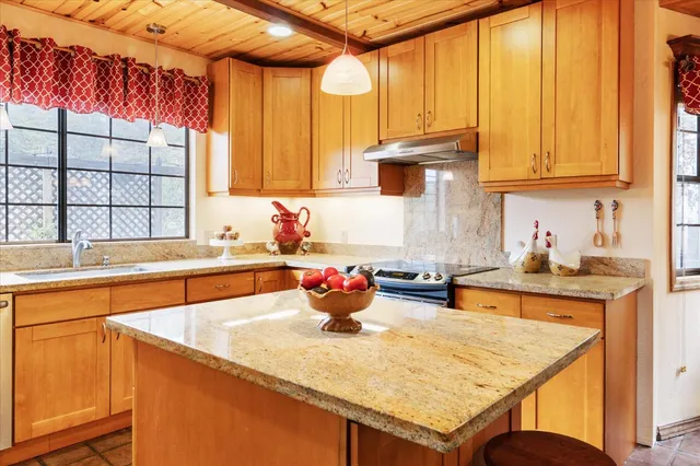 a kitchen with stainless steel appliances kitchen island wooden cabinets a window and a sink