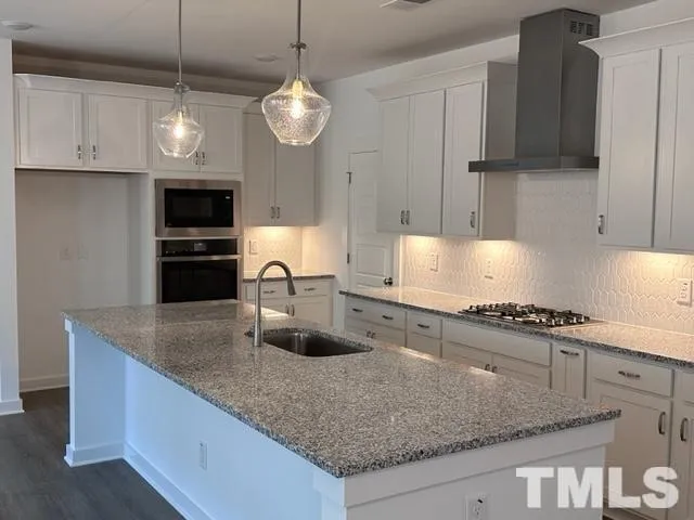 a kitchen with stainless steel appliances granite countertop a sink a stove and a granite counter top