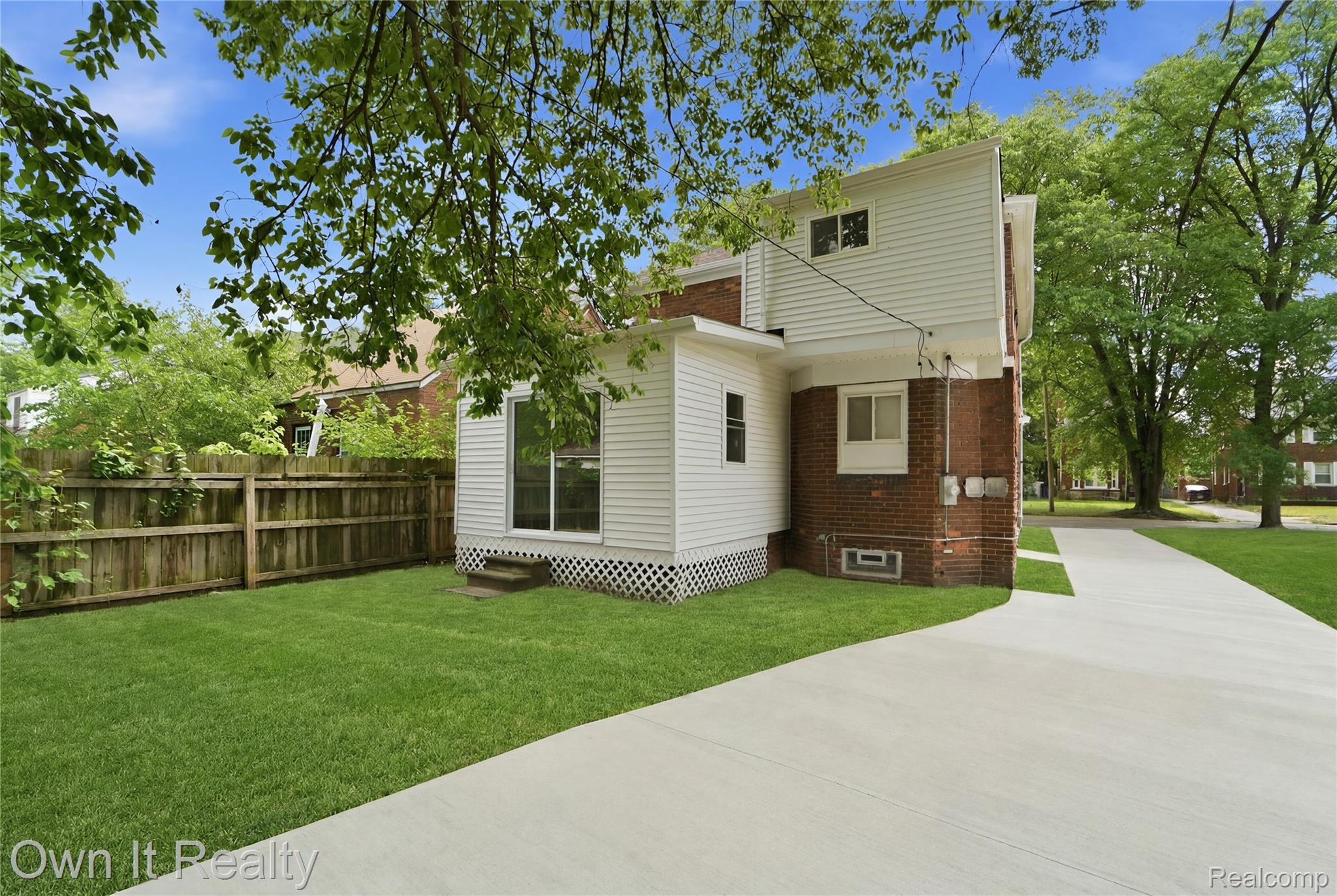 17351 Appoline Street Detroit, MI 48235 - Photo 29 of 34 Expansive rear yard featuring a manicured lawn, wood privacy fencing, and a concrete driveway