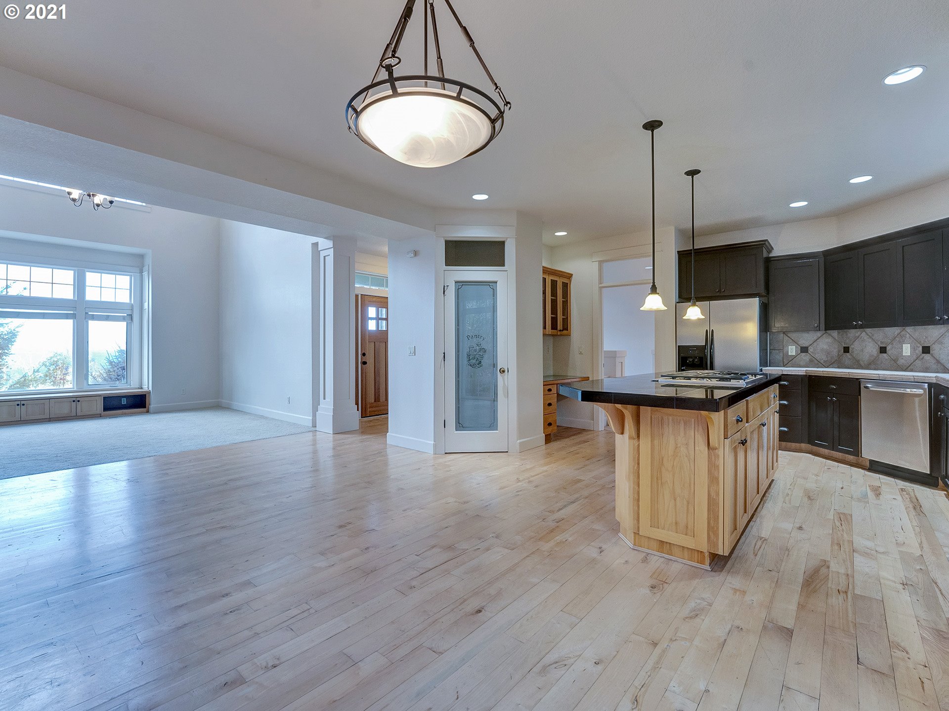 10248 Southeast Nicole Loop Happy Valley, OR 97086 - Photo 11 of 32 a view of kitchen with stainless steel appliances granite countertop a stove top oven a refrigerator and a dining table with wooden floor