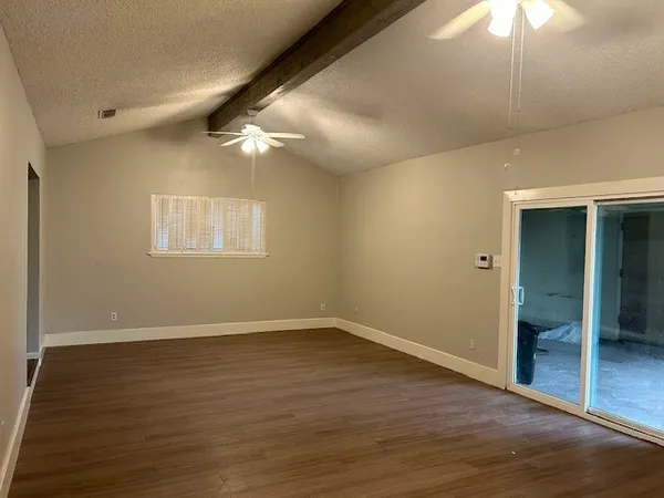 an empty room with wooden floor fan and windows