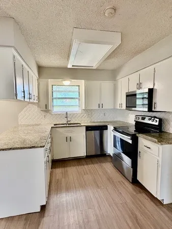 a kitchen with stainless steel appliances granite countertop wooden cabinets granite counter tops and a hard wood floors