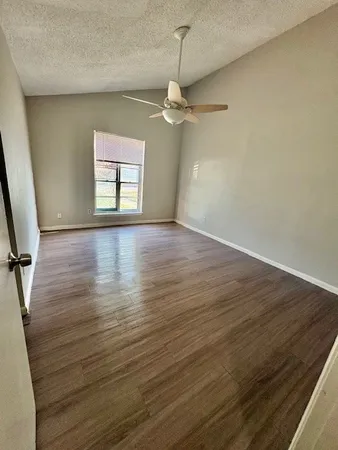 an empty room with wooden floor chandelier fan and windows