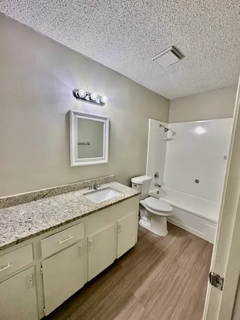 a bathroom with a granite countertop sink toilet and shower