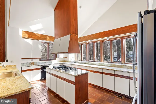 a view of a kitchen with kitchen island granite countertop a sink window and stainless steel appliances