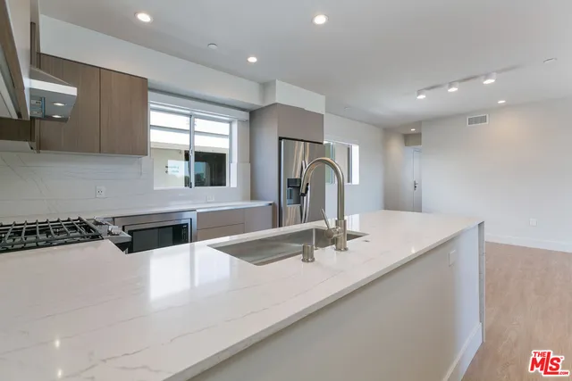 a kitchen with stainless steel appliances granite countertop a sink a stove and a refrigerator