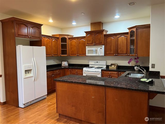 a kitchen with stainless steel appliances granite countertop a refrigerator a sink and a stove
