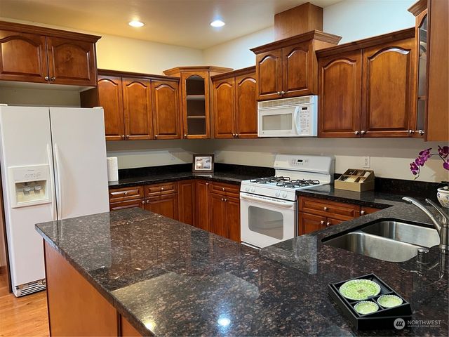 a kitchen with stainless steel appliances granite countertop a sink a stove and a wooden cabinets