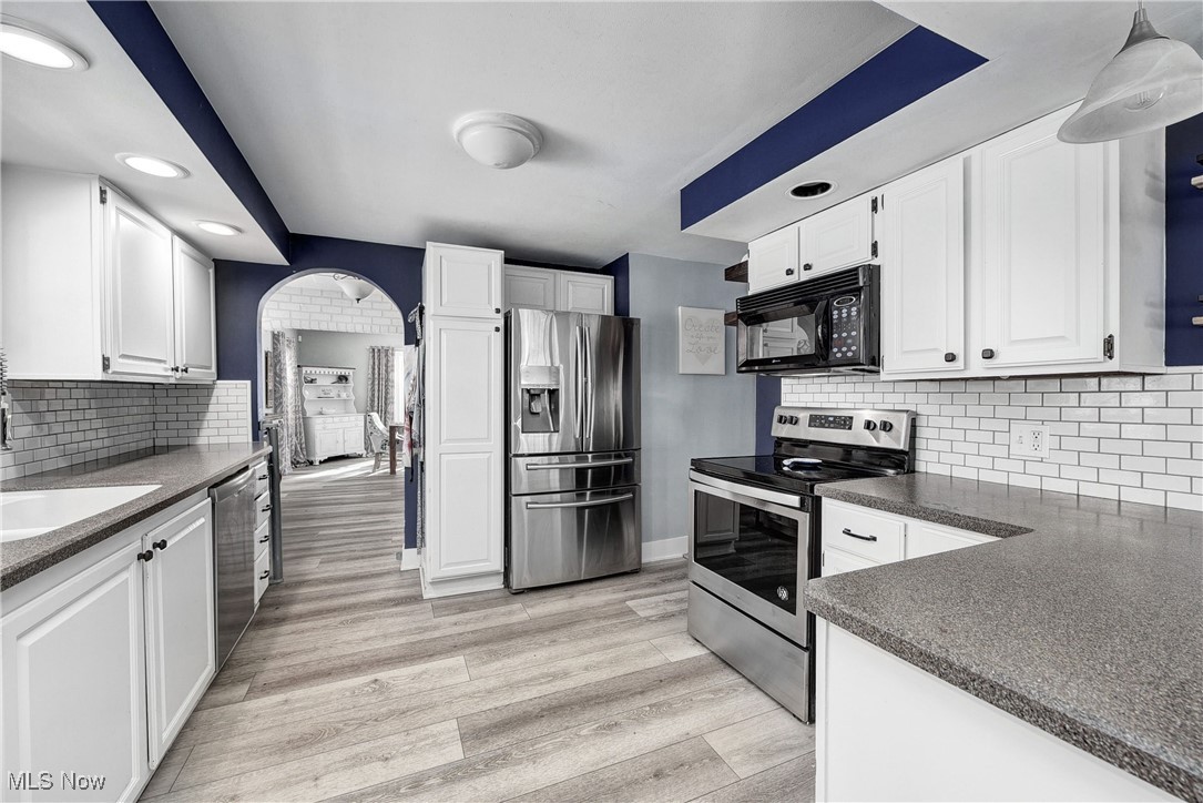 5927 Highland Road Highland Heights, OH 44143 - Photo 6 of 22 Kitchen featuring tasteful backsplash, appliances with stainless steel finishes, pendant lighting, white cabinets, and light wood-type flooring