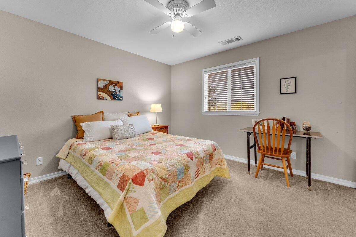 12269 Dry Creek Road Bella Vista, CA 96008 - Photo 25 of 74 a spacious bedroom with a bed and a chandelier