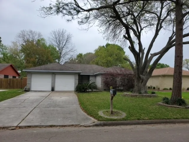 a front view of a house with a yard and large tree