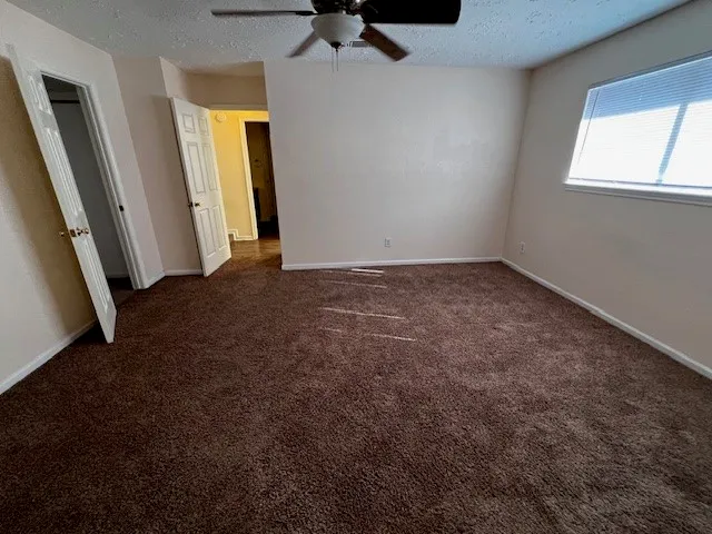 an empty room with a window and a ceiling fan