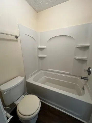 a white toilet sitting next to a bath tub