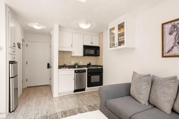 a living room with stainless steel appliances kitchen island granite countertop a refrigerator and a stove top oven