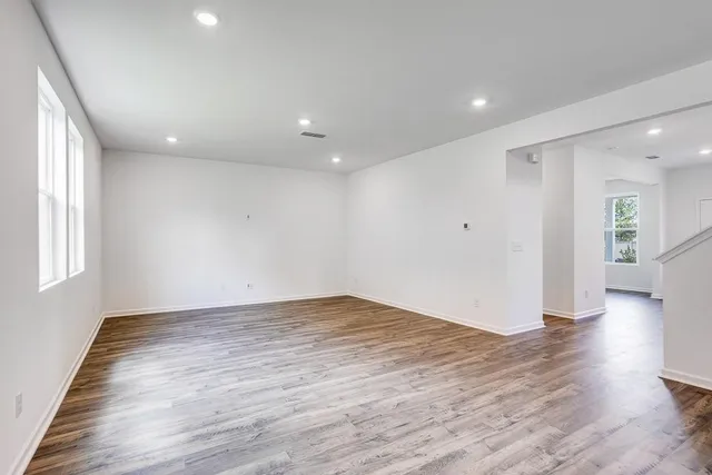 an empty room with wooden floor and windows