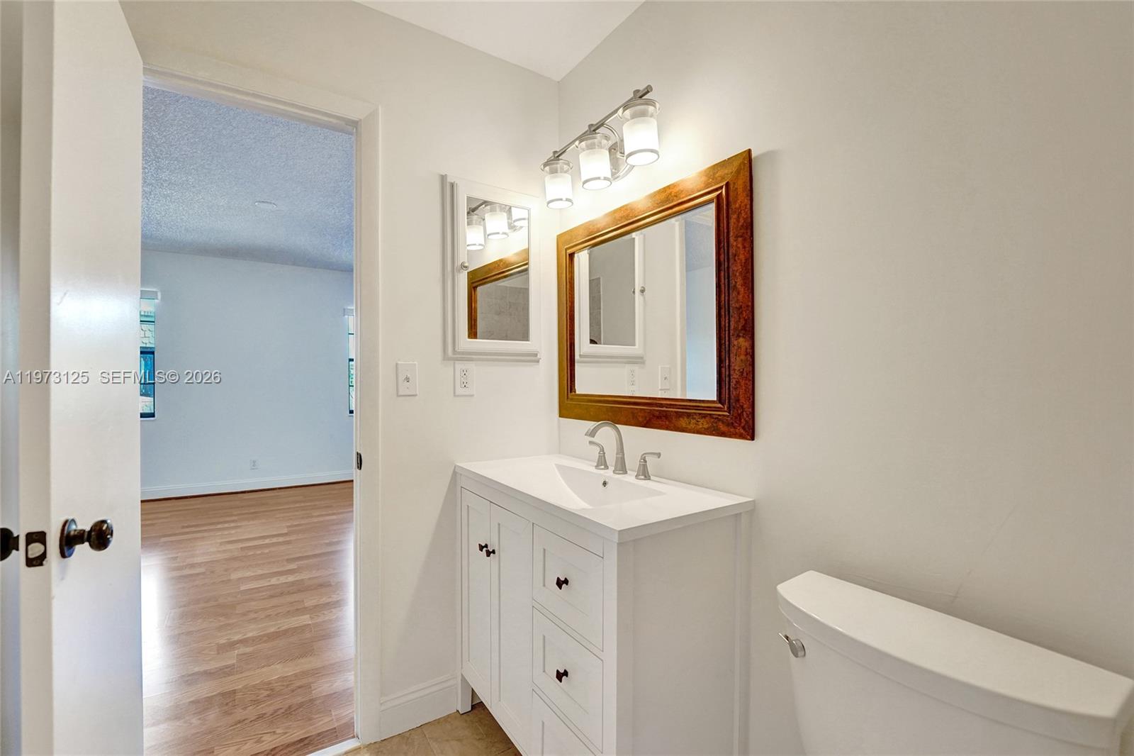 9340 Southwest 61st Way, Unit B Boca Raton, FL 33428 - Photo 13 of 25 a bathroom with a toilet sink and mirror