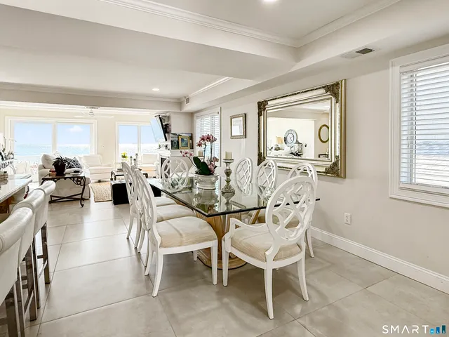 a view of a dining room and livingroom with furniture wooden floor a rug a painting and a chandelier