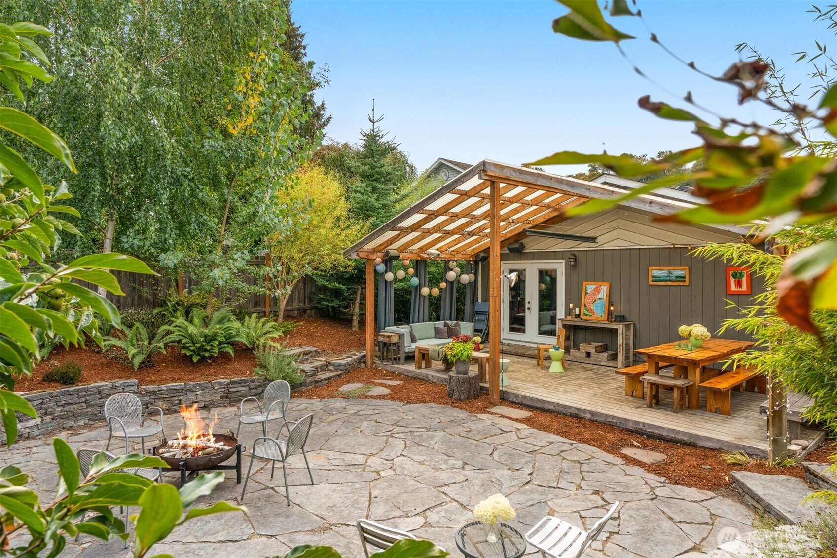 a view of a patio with table and chairs potted plants and large tree